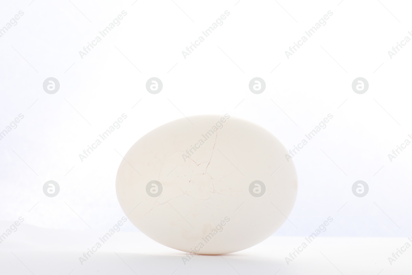 Photo of One egg with cracked shell on white background