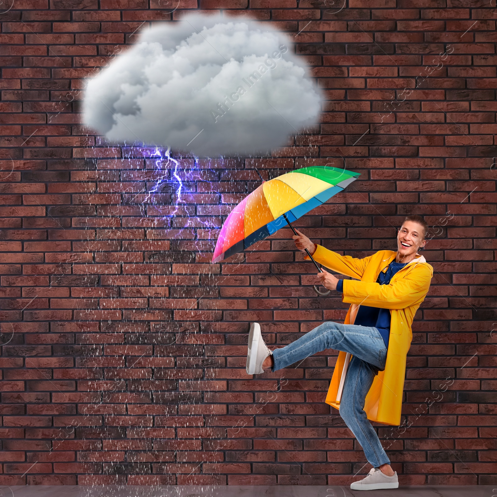 Image of Happy man protecting himself from thunderstorm with rainbow umbrella