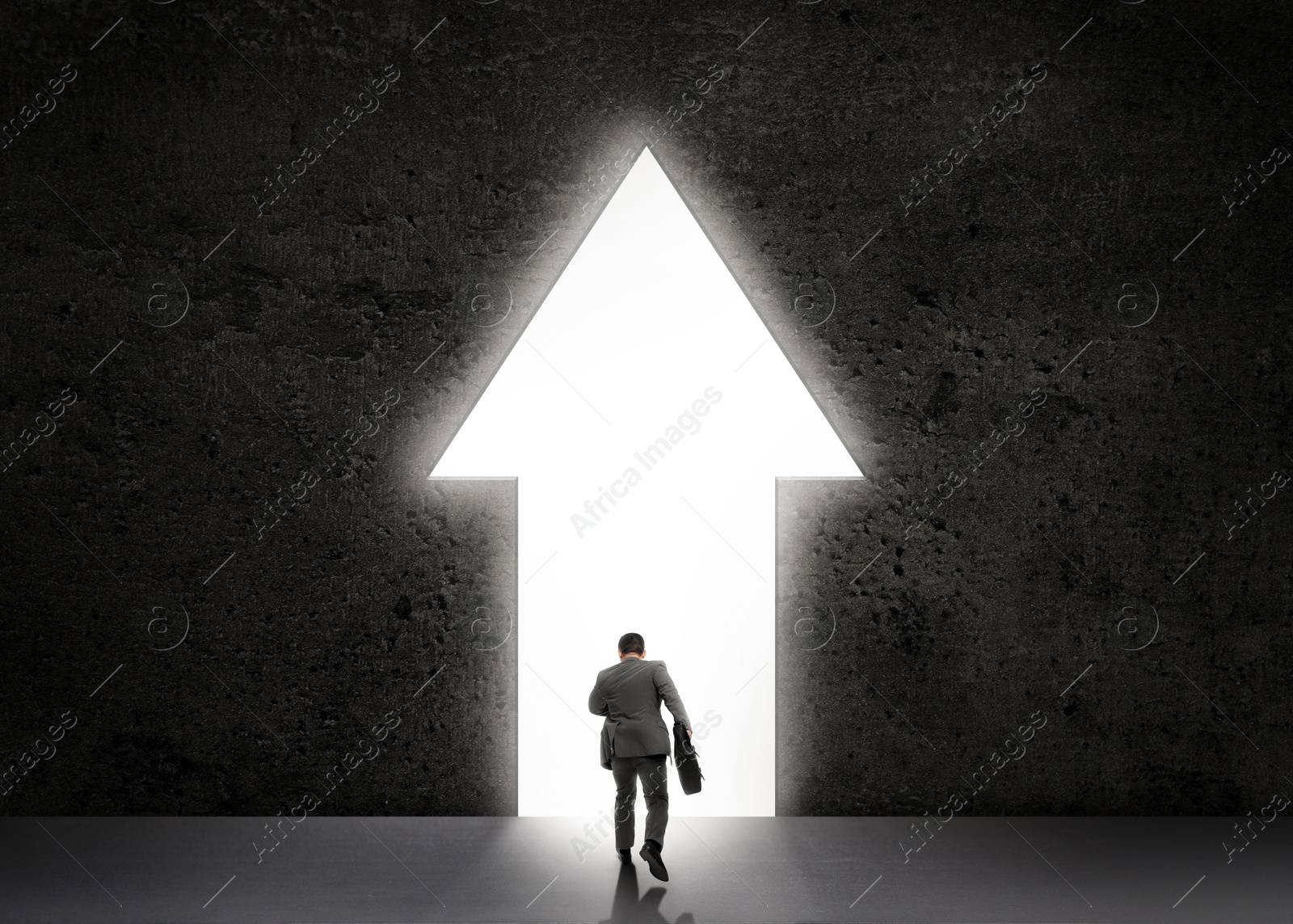 Image of Businessman walking towards arrow-shaped hole in dark stone wall. Idea, successful strategy, moving forward