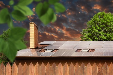 Image of Green energy. House with solar panels on roof at sunset