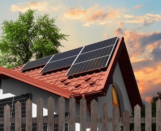 Image of Green energy. House with solar panels on roof at sunset