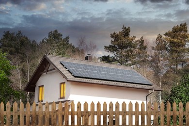 Image of Green energy. House with solar panels on roof at sunset