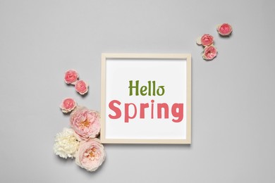 Image of Hello Spring card in frame and beautiful flowers on grey background, flat lay