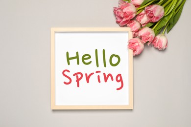 Image of Hello Spring card in frame and beautiful tulips on light grey background, flat lay