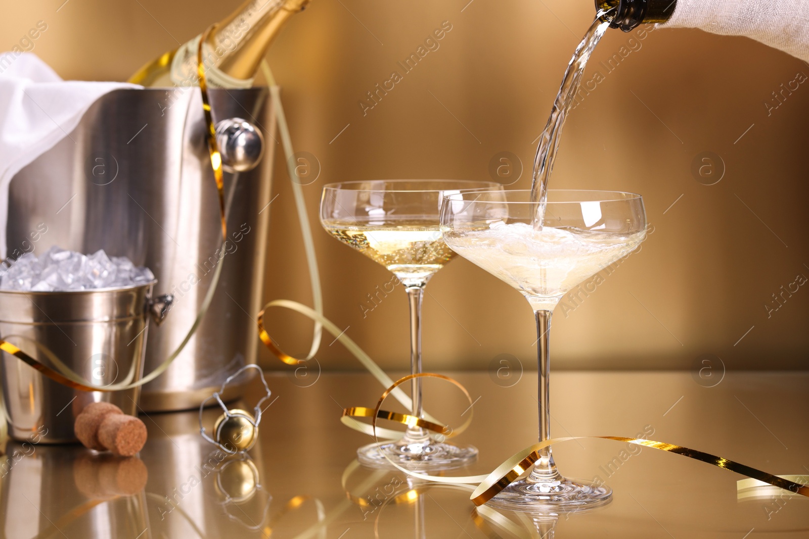 Photo of Pouring champagne into glass against golden background, closeup