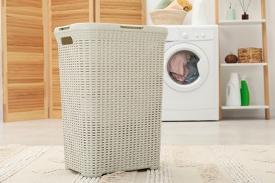 Photo of Wicker laundry basket on floor in bathroom