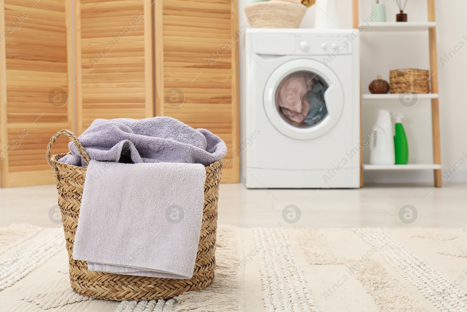 Photo of Wicker basket full of laundry in bathroom