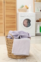 Photo of Wicker basket full of laundry in bathroom