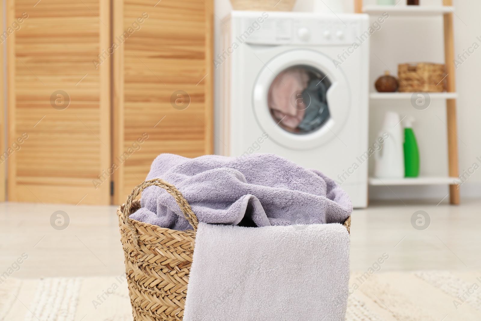 Photo of Wicker basket full of laundry in bathroom