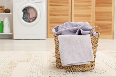 Photo of Wicker basket full of laundry in bathroom