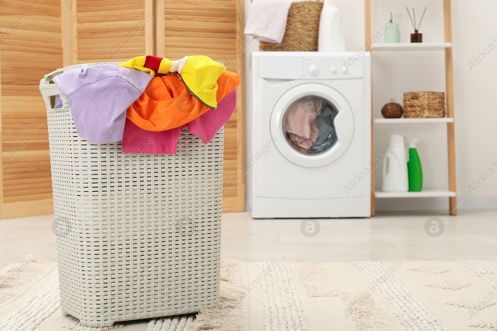 Photo of Wicker basket full of laundry in bathroom