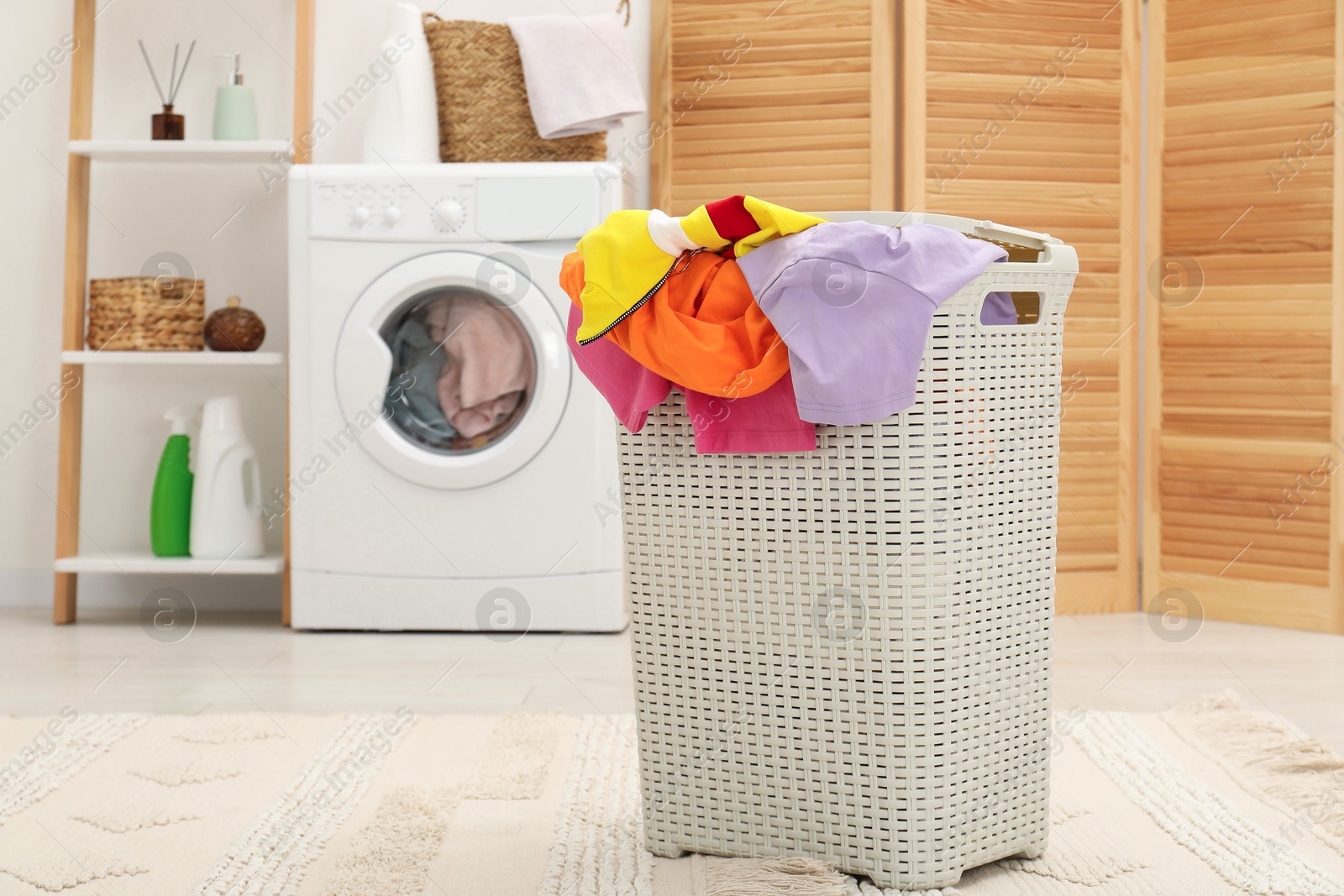 Photo of Wicker basket full of laundry in bathroom