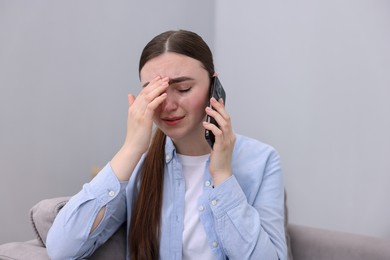 Photo of Stressed woman calling hotline for mental health help in armchair at home