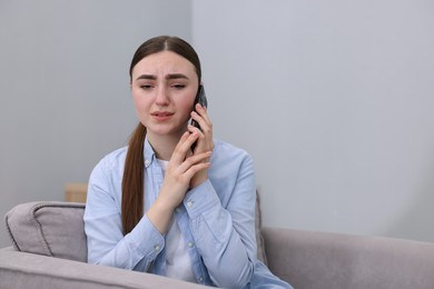 Photo of Stressed woman calling hotline for mental health help in armchair at home