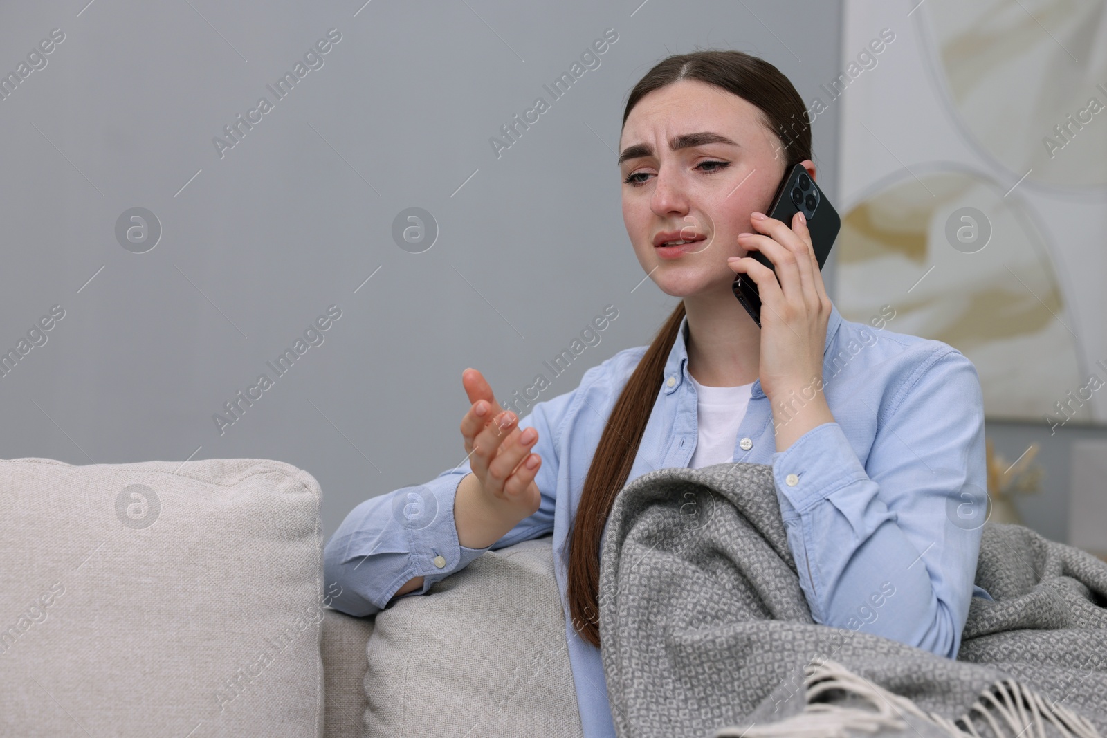 Photo of Depressed woman calling hotline for mental health help on sofa at home. Space for text