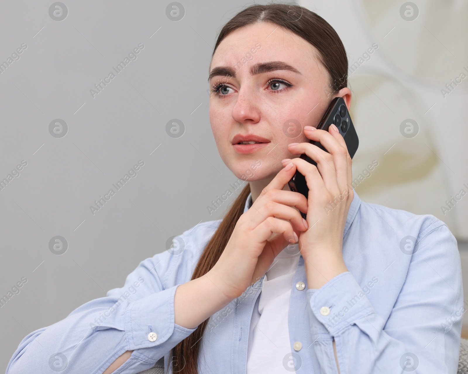 Photo of Depressed woman calling hotline for mental health help on sofa at home. Space for text