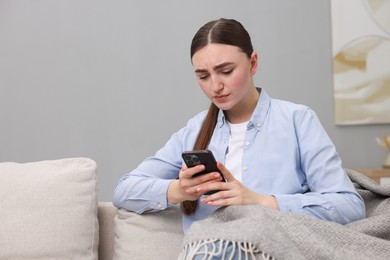 Photo of Depressed woman calling hotline for mental health help on sofa at home. Space for text