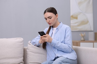 Photo of Depressed woman calling hotline for mental health help on sofa at home