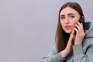 Photo of Stressed woman calling hotline for mental health help on grey background. Space for text