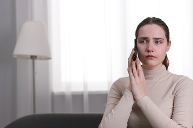 Photo of Depressed woman calling hotline for mental health help on sofa at home. Space for text