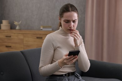 Photo of Depressed woman calling hotline for mental health help on sofa at home