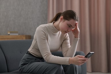 Photo of Depressed woman calling hotline for mental health help on sofa at home