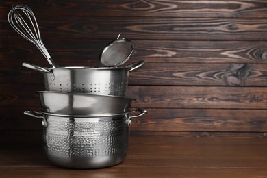 Photo of Dishware and cooking utensils on wooden table, space for text