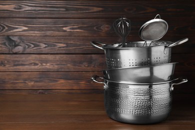 Photo of Dishware and cooking utensils on wooden table, space for text