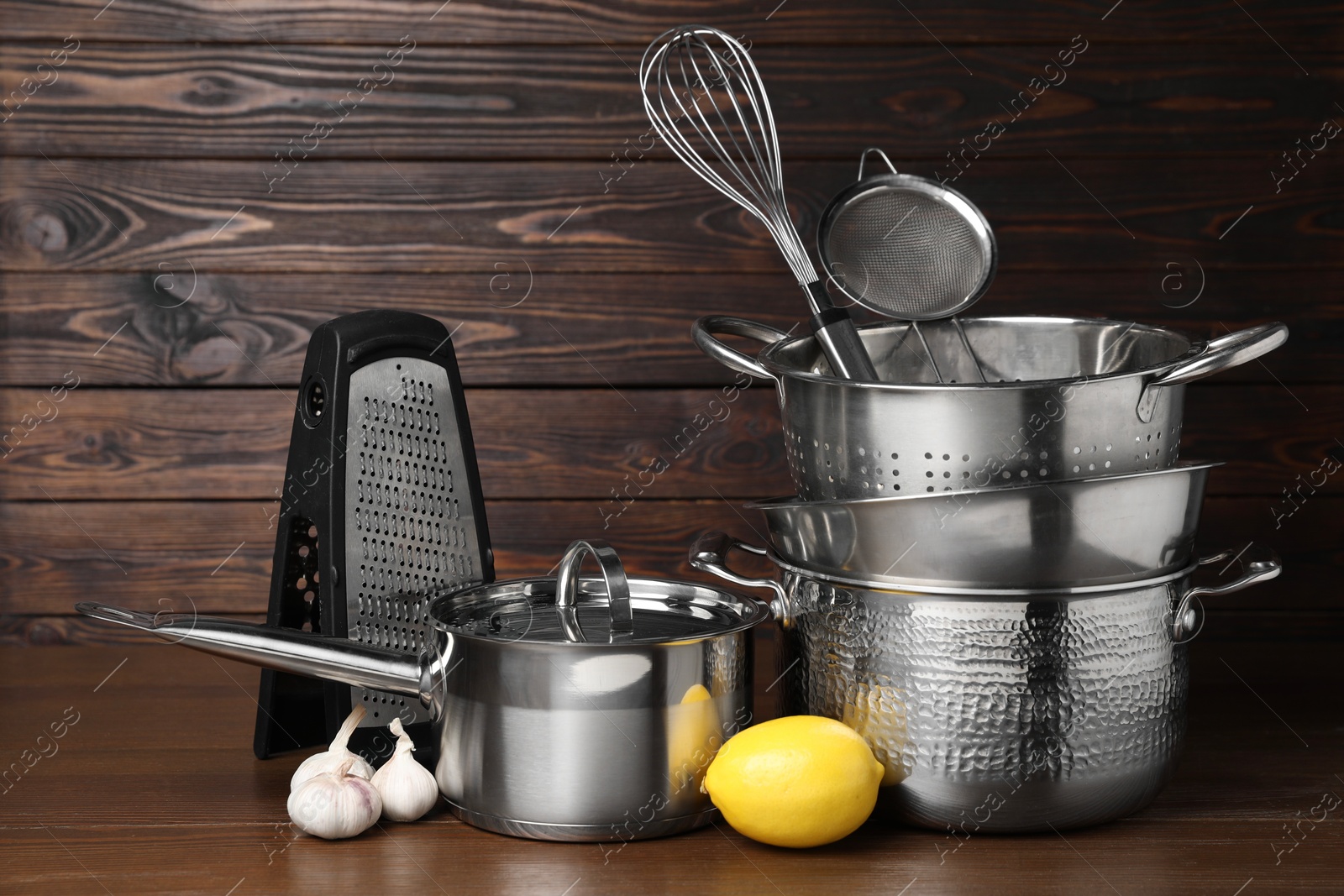 Photo of Dishware, cooking utensils with lemon on wooden table