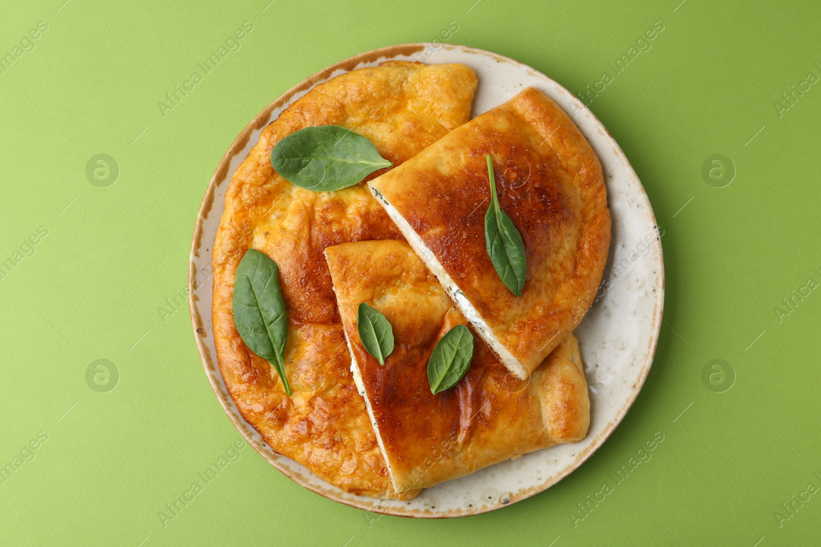 Photo of Tasty calzones with basil and cheese on green background, top view