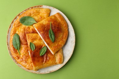 Photo of Tasty calzones with basil and cheese on green background, top view. Space for text