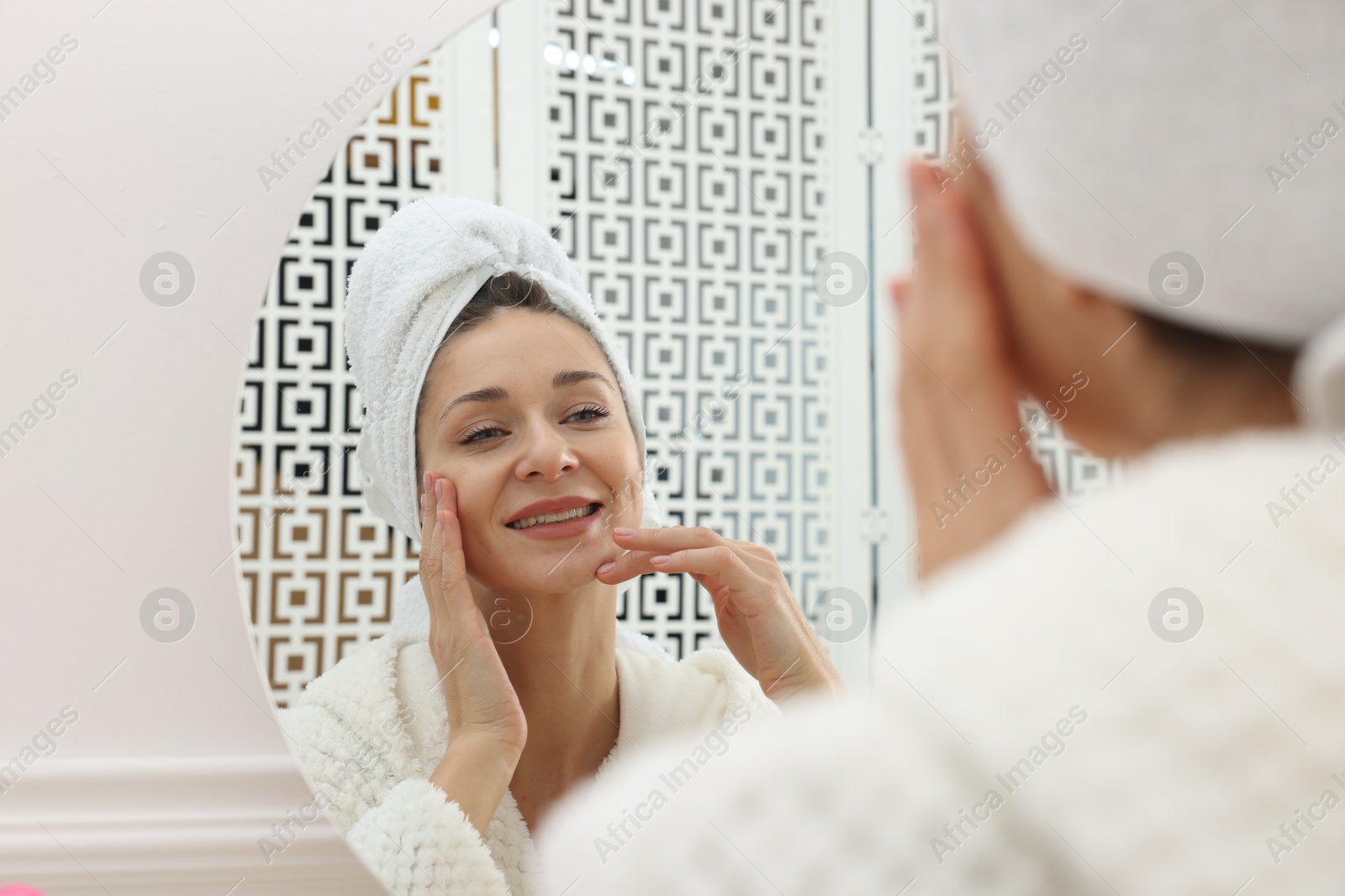 Photo of Spa day. Beautiful woman in bathrobe near mirror indoors