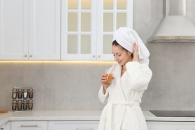 Photo of Beautiful woman with glass of juice after spa procedure in kitchen