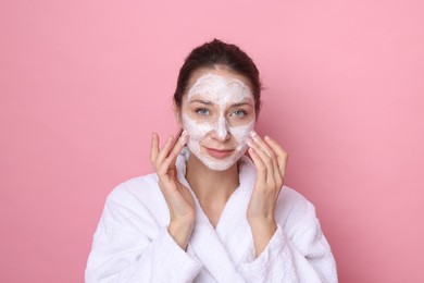 Photo of Spa day. Beautiful woman applying mask onto her face on pink background