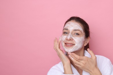 Photo of Spa day. Beautiful woman applying mask onto her face on pink background