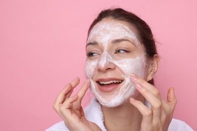 Photo of Spa day. Beautiful woman applying mask onto her face on pink background