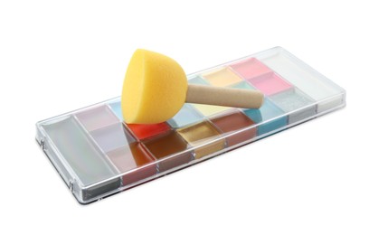 Photo of Bright face paint palette and sponge isolated on white