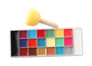 Photo of Bright face paint palette and sponge isolated on white, top view