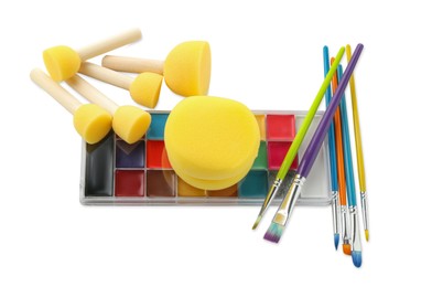 Photo of Bright face paint palette, brushes and sponges isolated on white, top view