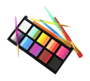 Photo of Bright face paint palette and brushes isolated on white, top view