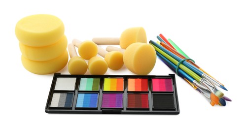 Photo of Bright face paint palette, brushes and sponges isolated on white