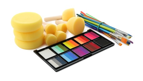 Photo of Bright face paint palette, brushes and sponges isolated on white