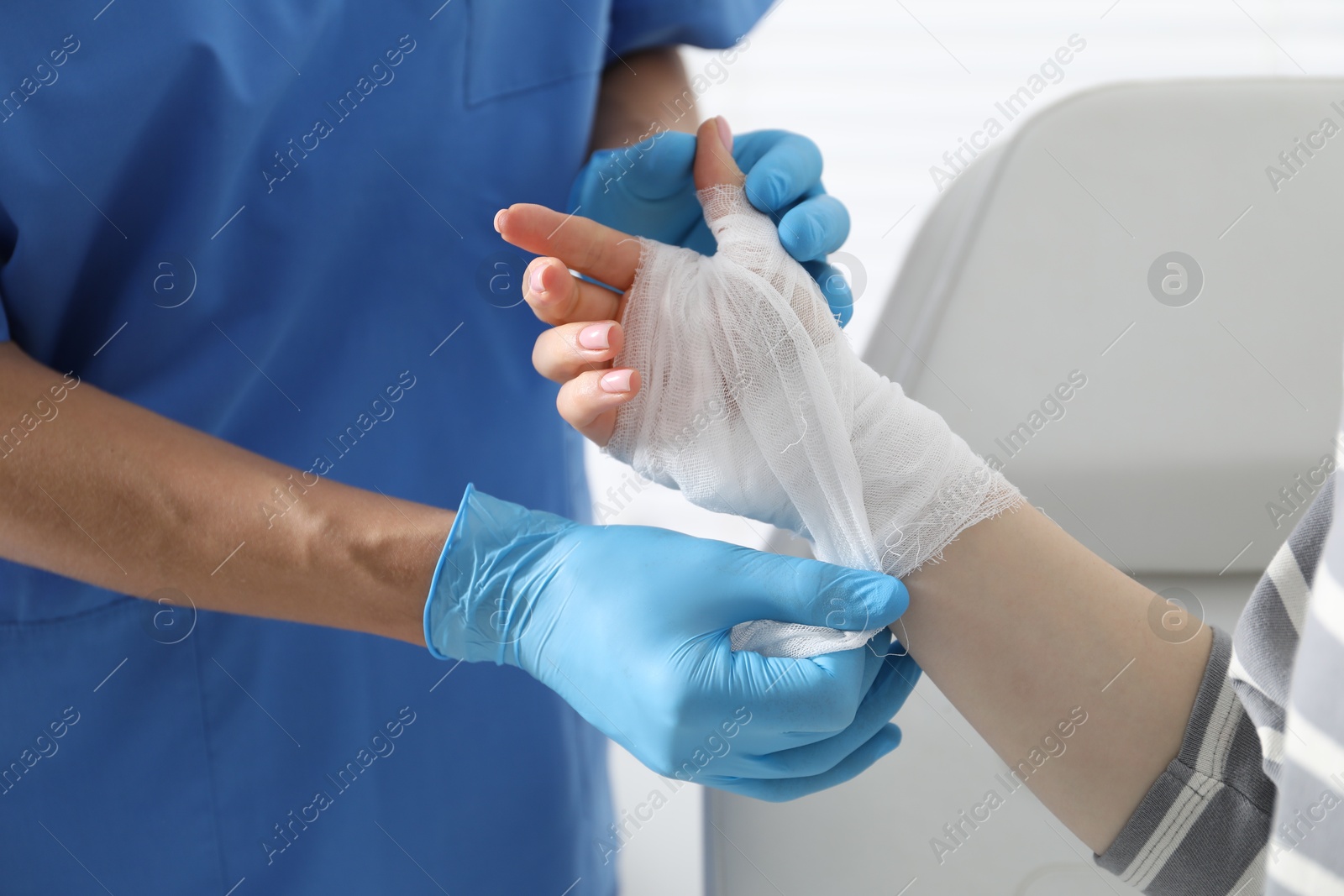 Photo of Doctor bandaging patient's hand in clinic, closeup