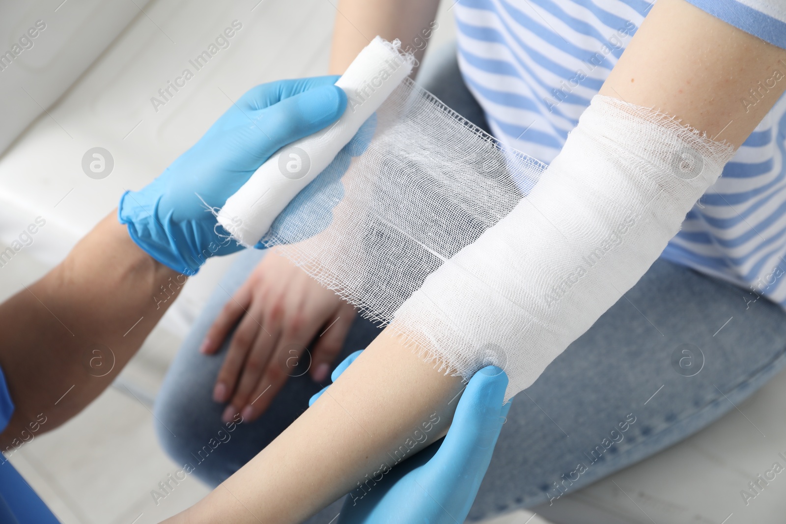 Photo of Doctor bandaging patient's elbow in clinic, closeup