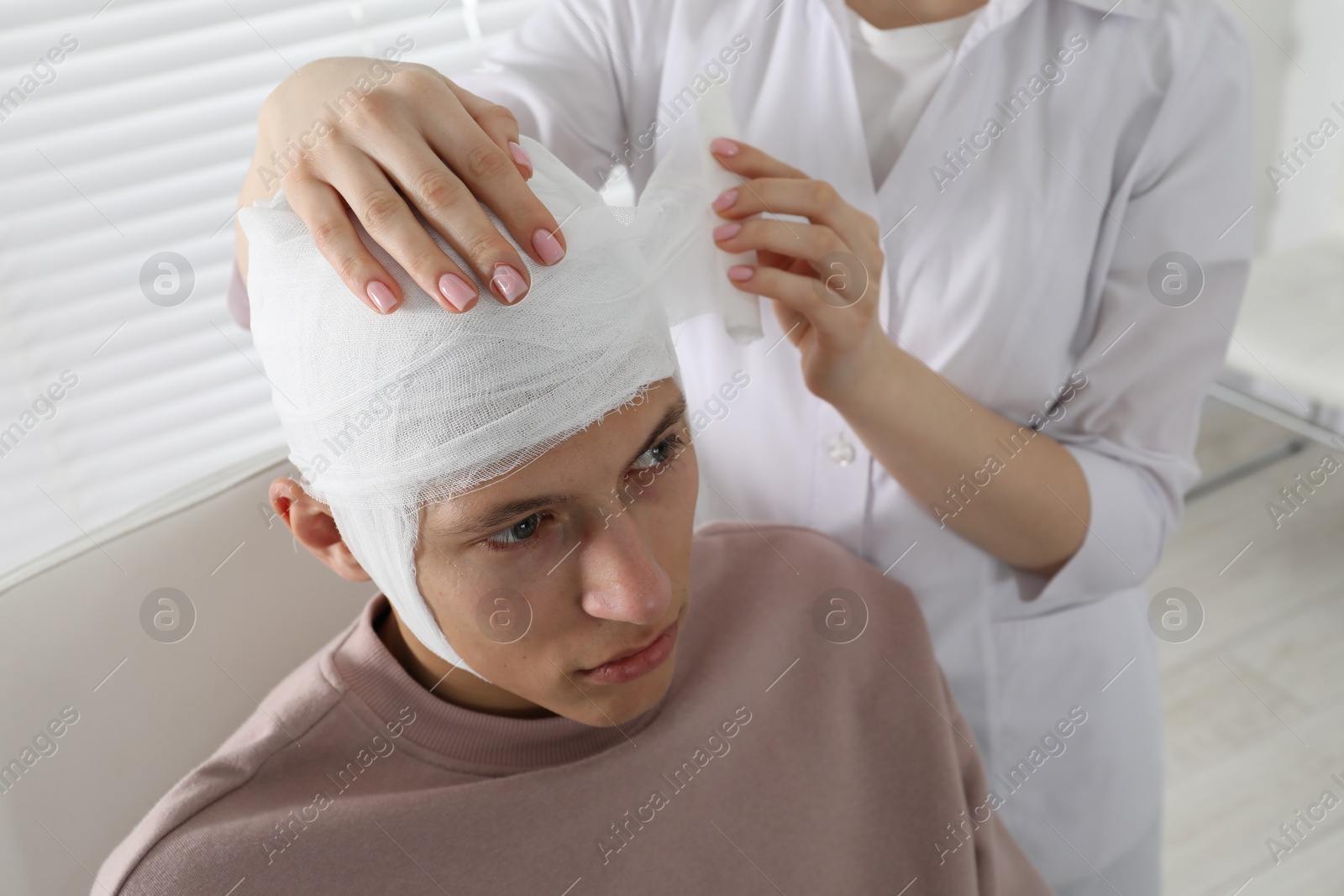 Photo of Doctor bandaging patient's head in clinic, closeup