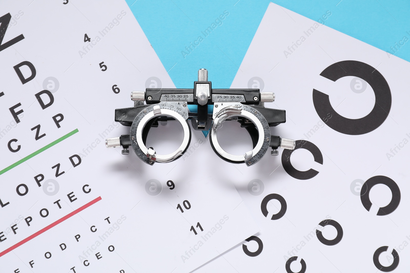 Photo of Vision test charts and trial frame on light blue background, top view