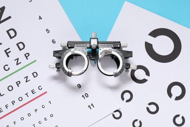 Photo of Vision test charts and trial frame on light blue background, top view