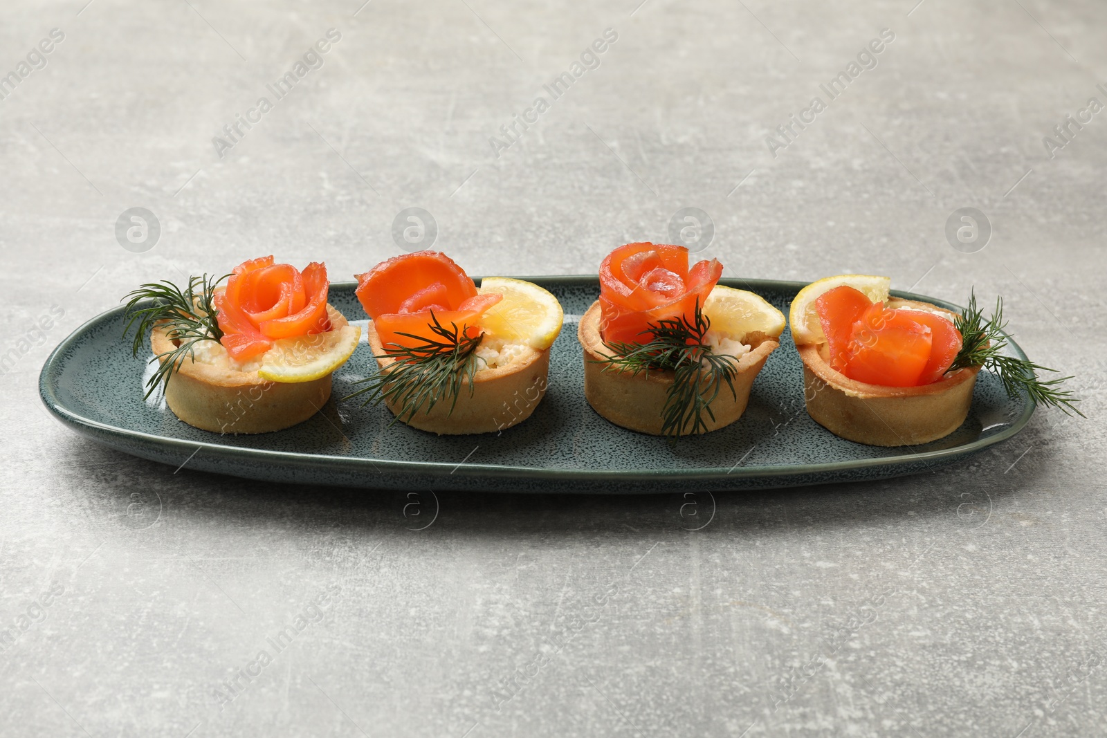 Photo of Tasty tartlets with delicious filling on grey table