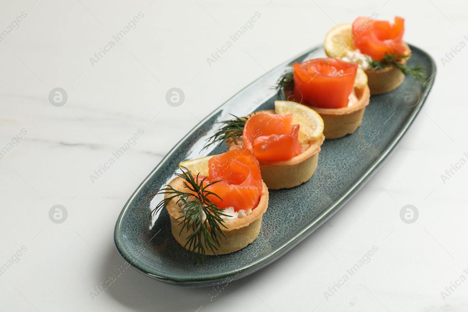 Photo of Tasty tartlets with delicious filling on white marble table, closeup