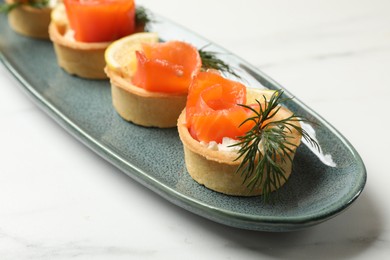 Photo of Tasty tartlets with delicious filling on white marble table, closeup